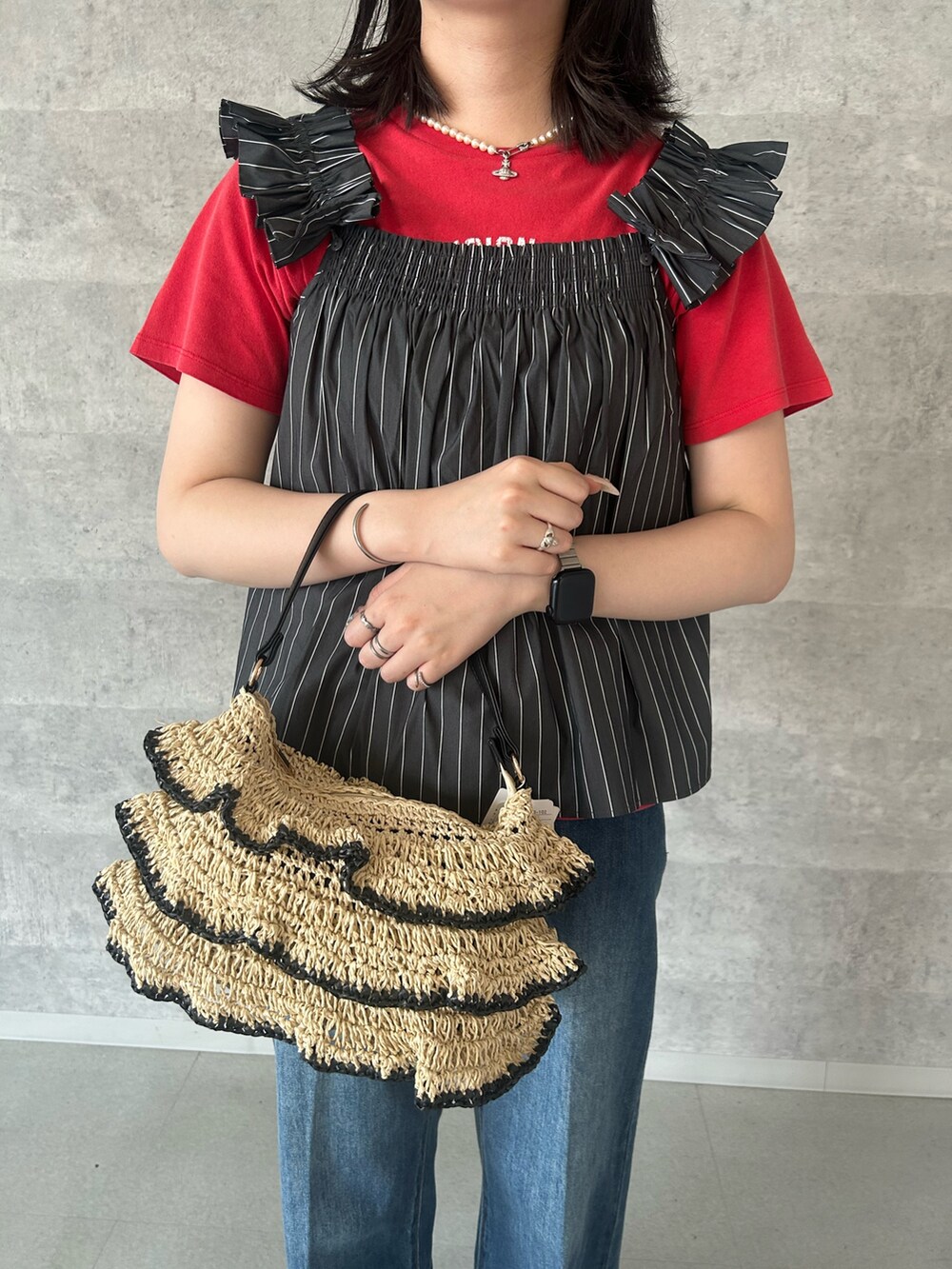 レッド系のTシャツ/カットソー、ブラック系のかごバッグ、ブルー系のデニムパンツを着用したレディースの夏コーディネートの2枚目の写真