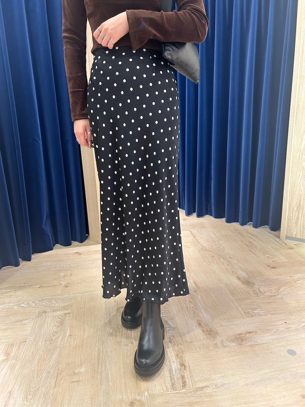 ブラウン系のTシャツ/カットソー、ブラック系のスカート、ブラック系のショルダーバッグを着用したレディースの秋コーディネートの3枚目の写真