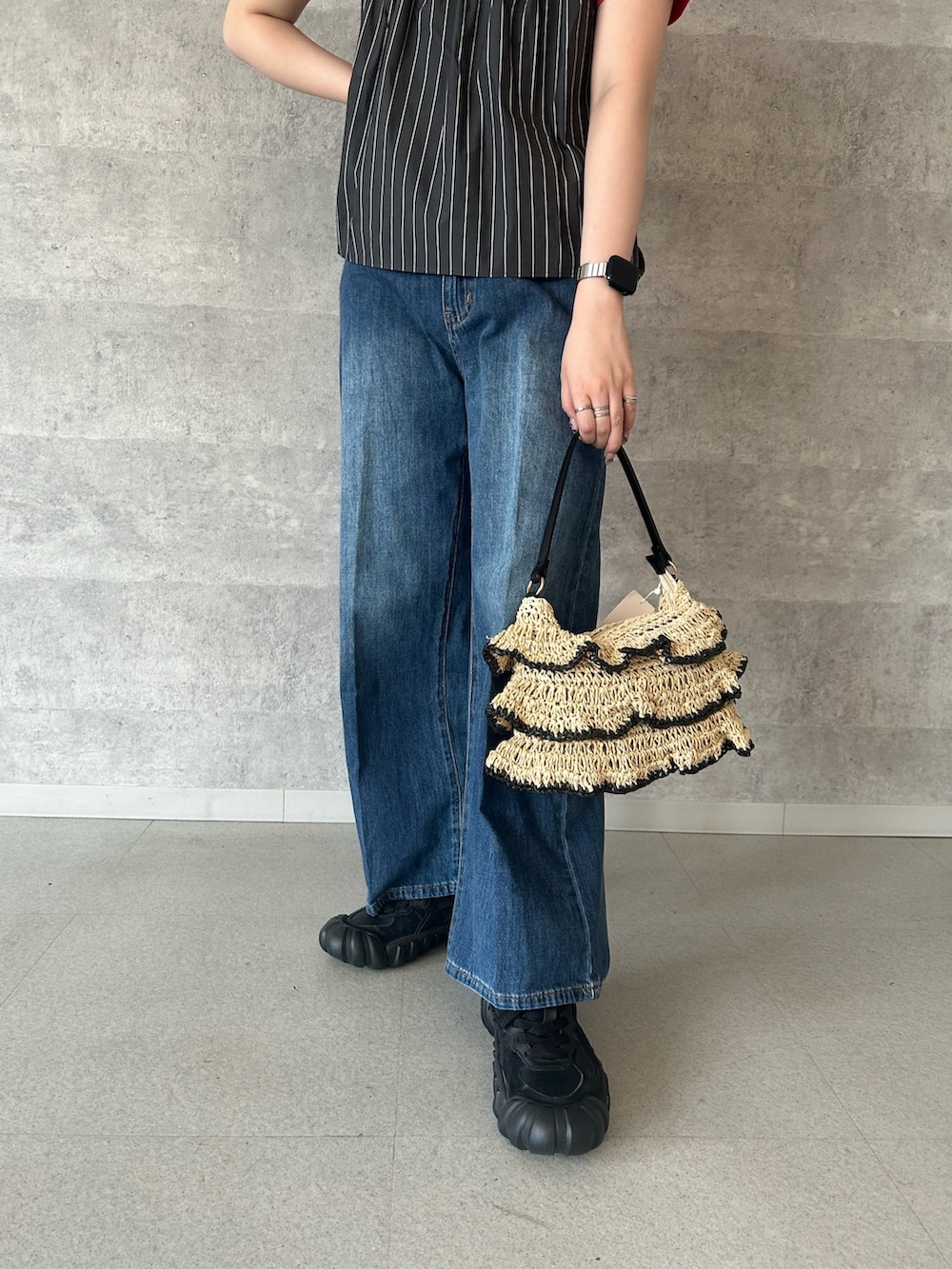 レッド系のTシャツ/カットソー、ブラック系のかごバッグ、ブルー系のデニムパンツを着用したレディースの夏コーディネートの3枚目の写真