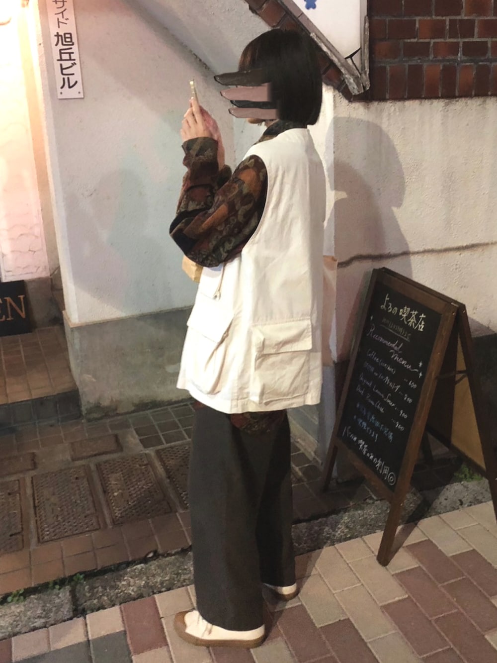 ホワイト系のベスト、ブラウン系のパンツ、ホワイト系のスニーカーを着用したレディースの秋コーディネートの2枚目の写真