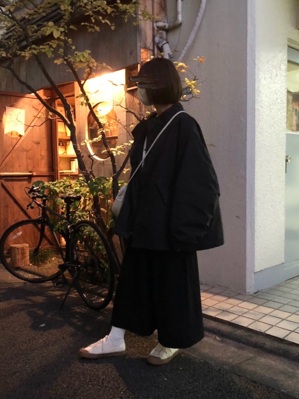 ブラック系のモッズコート、ホワイト系のボストンバッグ、ブラック系のワンピースを着用したレディースの冬コーディネートの3枚目の写真