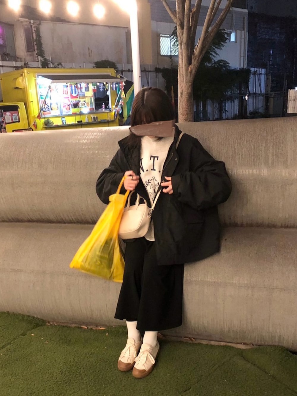 ブラック系のモッズコート、ホワイト系のボストンバッグ、ブラック系のワンピースを着用したレディースの冬コーディネートの2枚目の写真