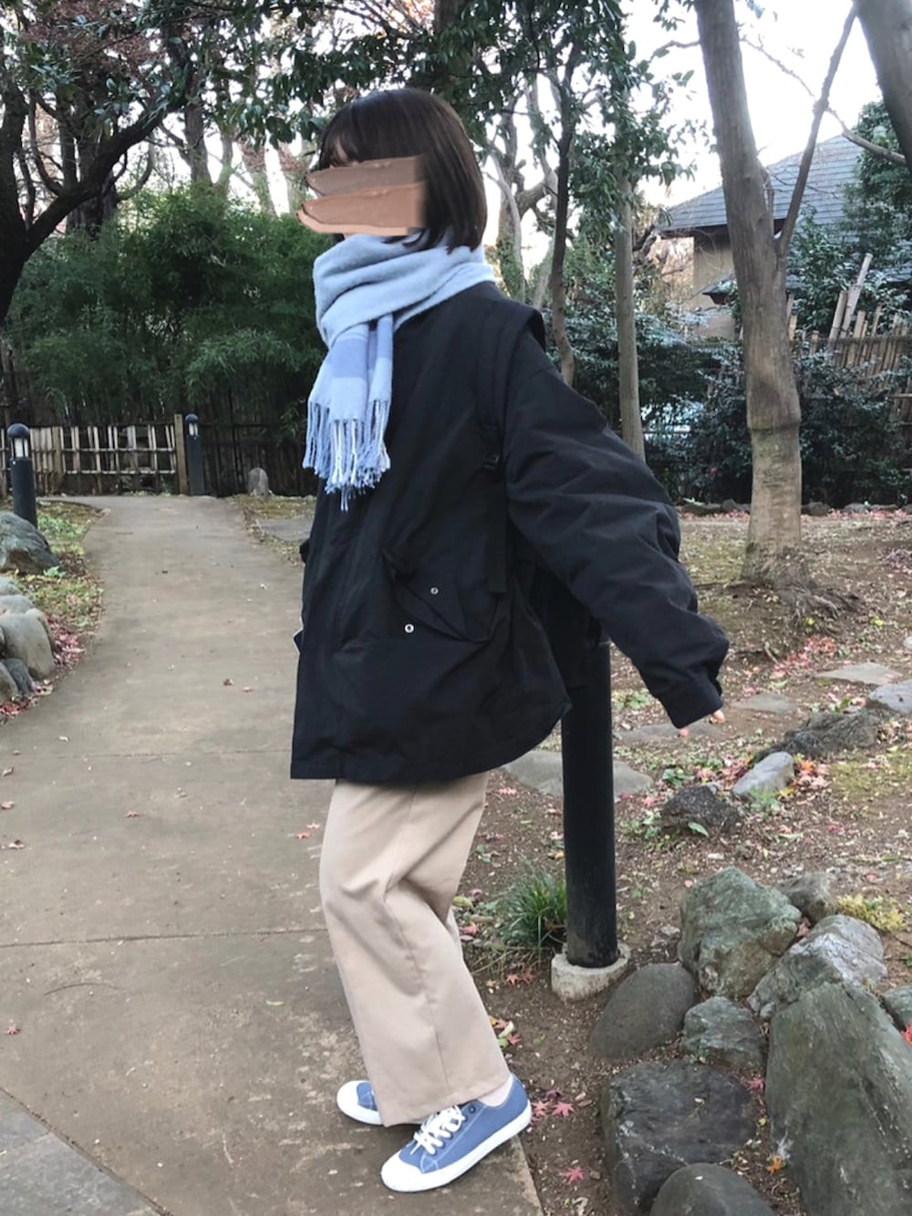 ブラック系のモッズコート、ベージュ系のパンツ、ブルー系のスニーカーを着用したレディースの冬コーディネートの2枚目の写真