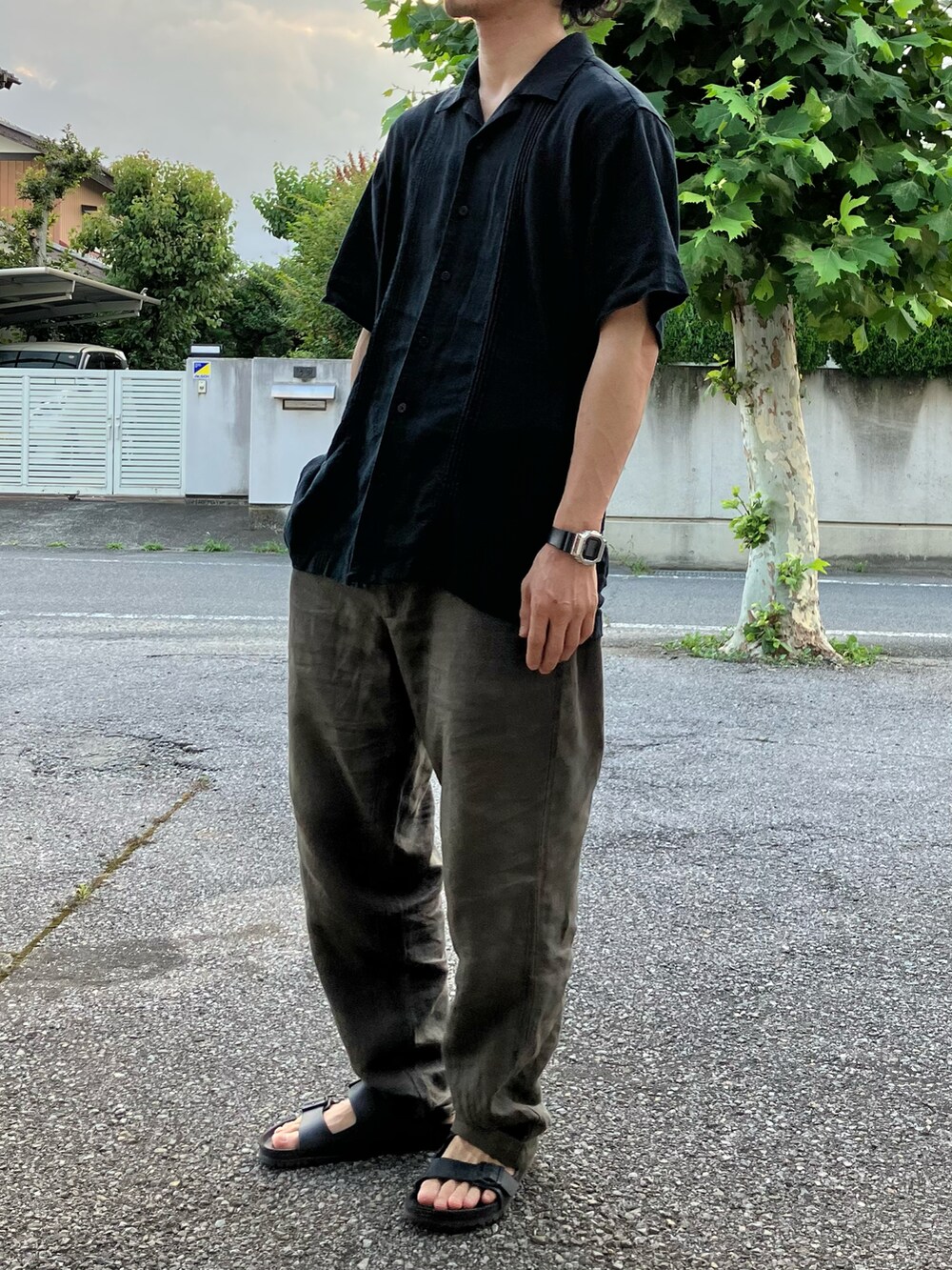 ブラウン系のパンツ、ブラック系のサンダル、シルバー系のデジタル腕時計を着用したメンズの夏コーディネートの3枚目の写真