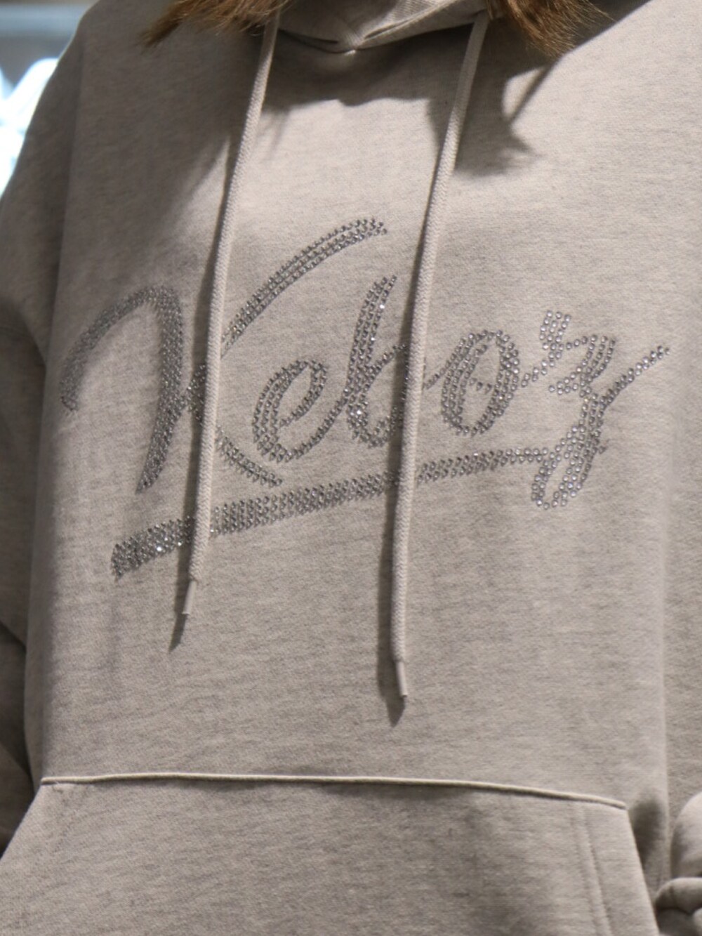 グレー系のパーカー、ベージュ系のチノパンツ、ブラック系のニットキャップ/ビーニーを着用したレディースの冬コーディネートの2枚目の写真