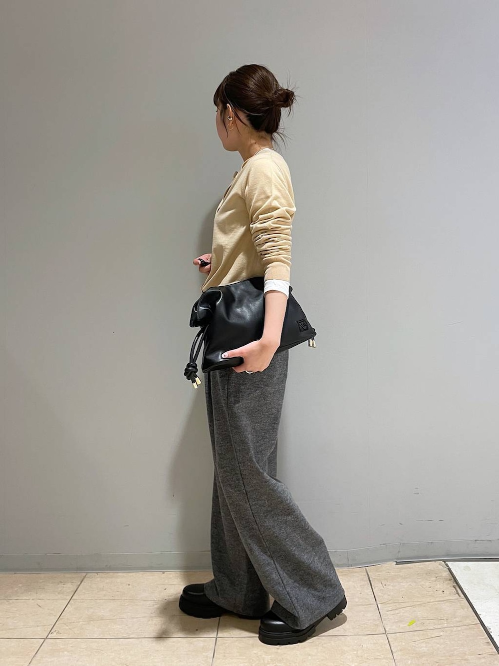 ブラック系のブーツ、ベージュ系のカーディガン/ボレロ、グレー系のスラックスを着用したレディースの冬コーディネートの2枚目の写真