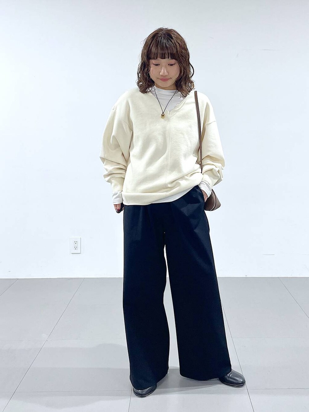 ブラウン系のショルダーバッグ、ブラック系のブーツ、ホワイト系のTシャツ/カットソーを着用したレディースの秋コーディネートの4枚目の写真