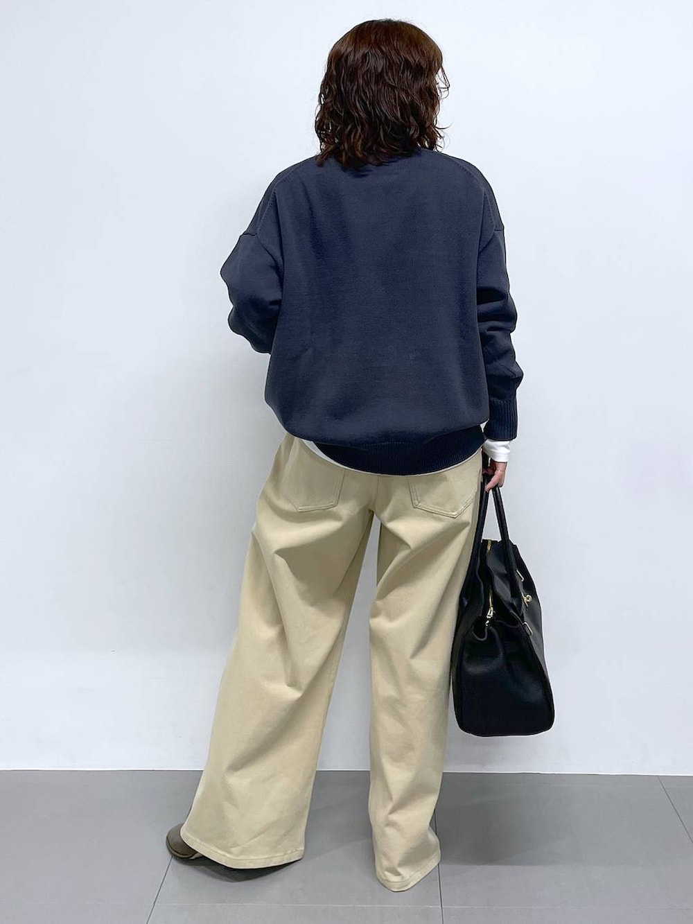 グレー系のニット/セーター、ベージュ系のデニムパンツを着用したレディースの冬コーディネートの3枚目の写真