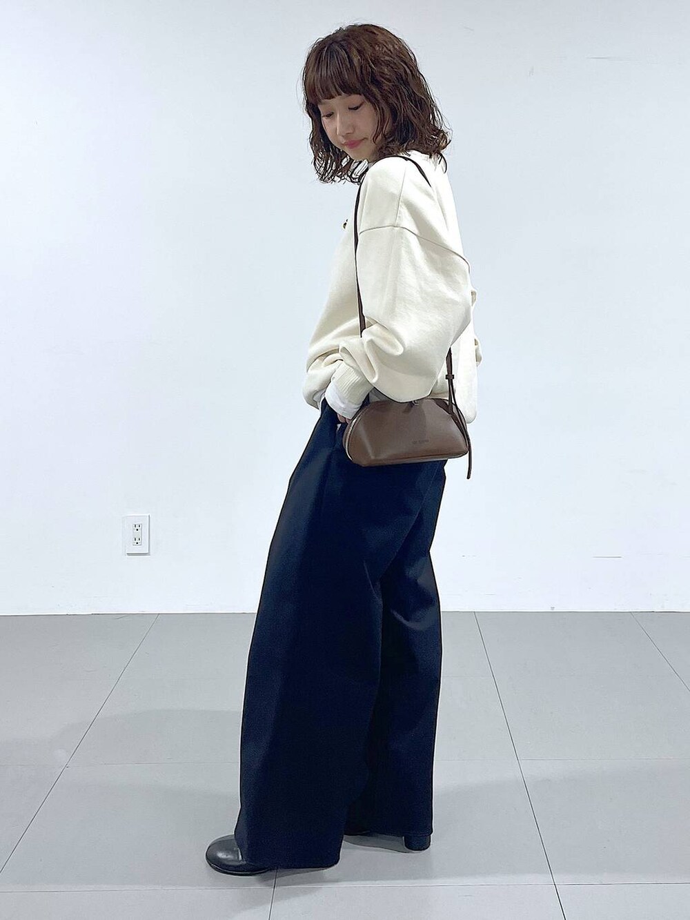 ブラウン系のショルダーバッグ、ブラック系のブーツ、ホワイト系のTシャツ/カットソーを着用したレディースの秋コーディネートの2枚目の写真