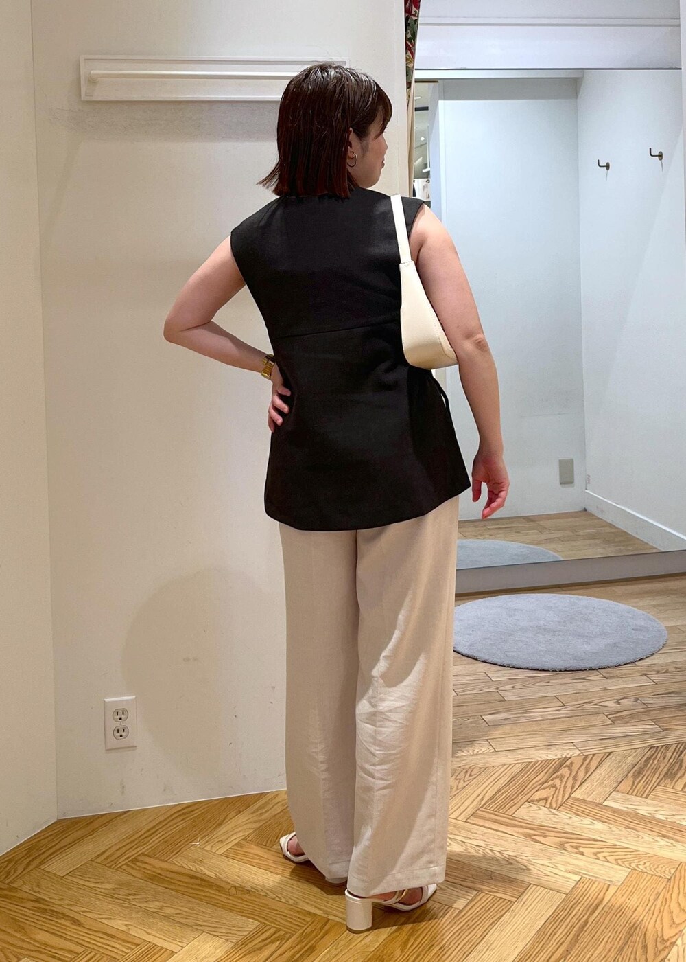 ホワイト系のハンドバッグ、ホワイト系のサンダル、ホワイト系のスラックスを着用したレディースの夏コーディネートの4枚目の写真