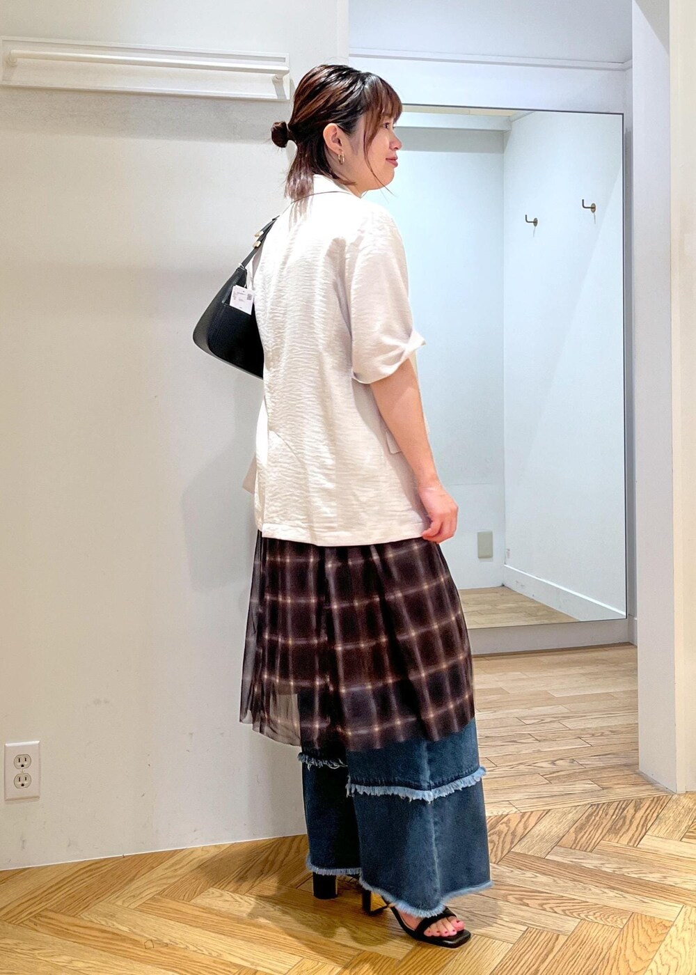 ブラック系のハンドバッグ、ブラック系のサンダル、ホワイト系のテーラードジャケットを着用したレディースの夏コーディネートの4枚目の写真