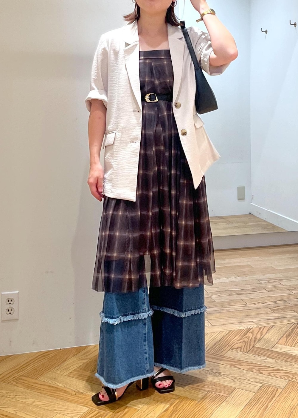 ブラック系のハンドバッグ、ブラック系のサンダル、ホワイト系のテーラードジャケットを着用したレディースの夏コーディネートの3枚目の写真