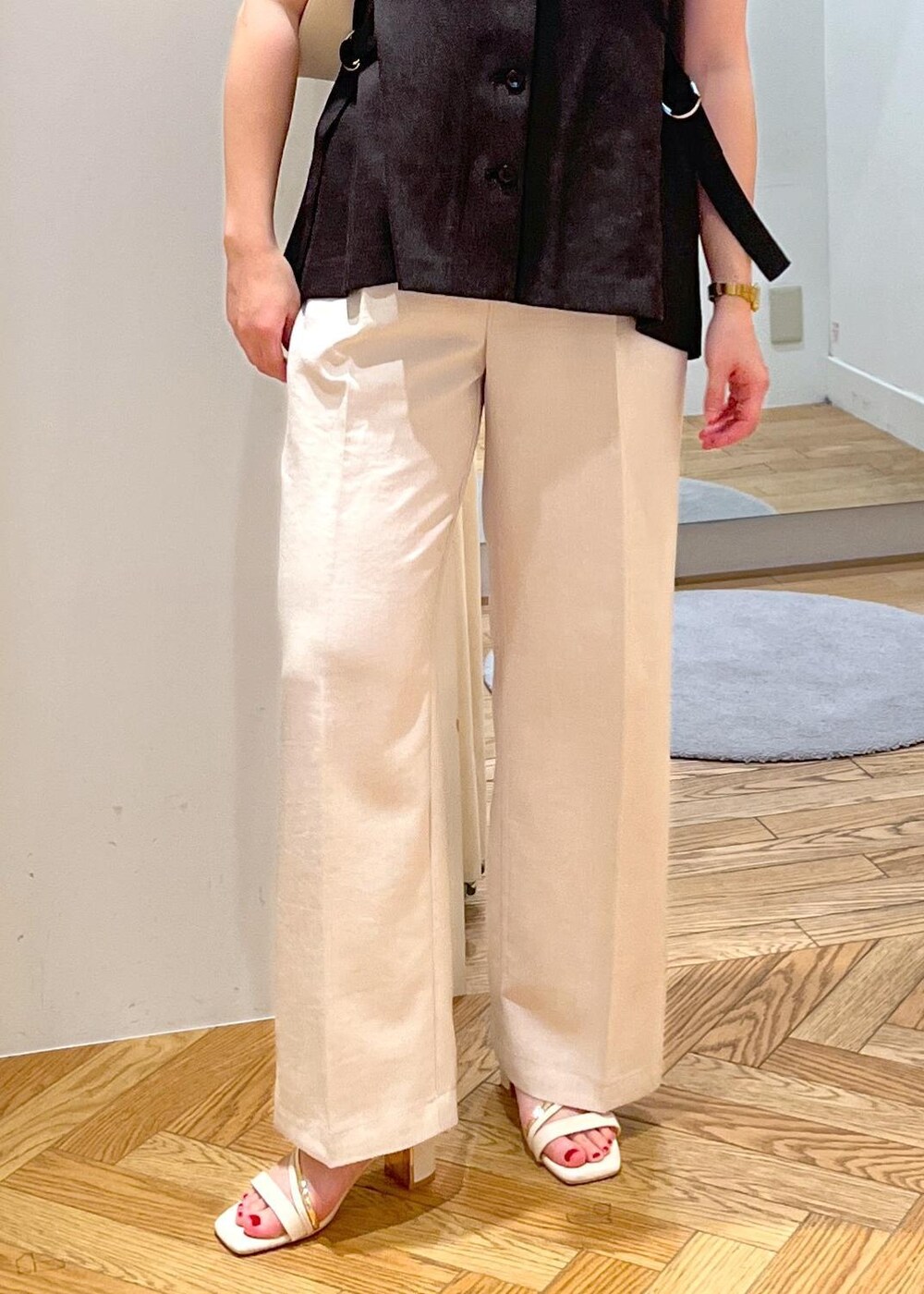 ホワイト系のハンドバッグ、ホワイト系のサンダル、ホワイト系のスラックスを着用したレディースの夏コーディネートの6枚目の写真