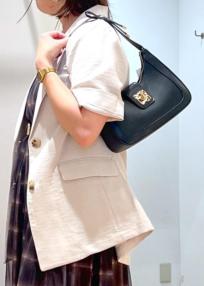 ブラック系のハンドバッグ、ブラック系のサンダル、ホワイト系のテーラードジャケットを着用したレディースの夏コーディネートの7枚目の写真