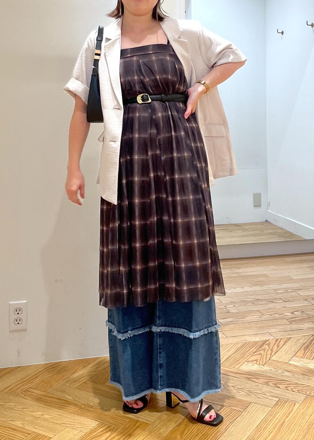 ブラック系のハンドバッグ、ブラック系のサンダル、ホワイト系のテーラードジャケットを着用したレディースの夏コーディネートの2枚目の写真