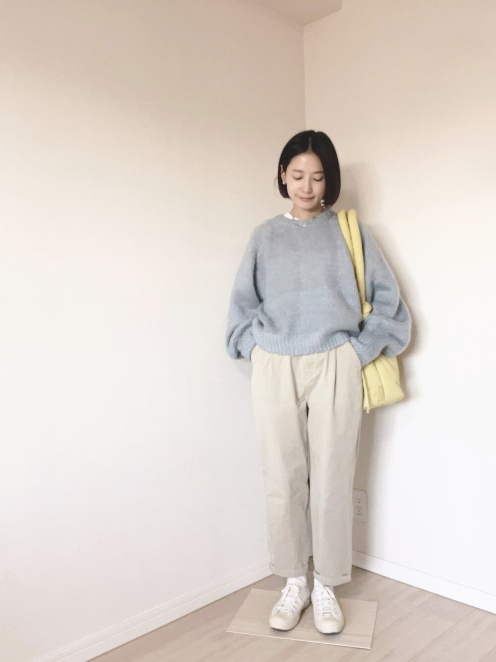 ブルー系のニット/セーター、イエロー系のバッグ、ベージュ系のチノパンツを着用したレディースの冬コーディネートの2枚目の写真
