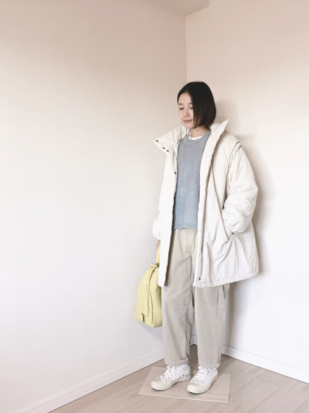 ブルー系のニット/セーター、イエロー系のバッグ、ベージュ系のチノパンツを着用したレディースの冬コーディネートの3枚目の写真