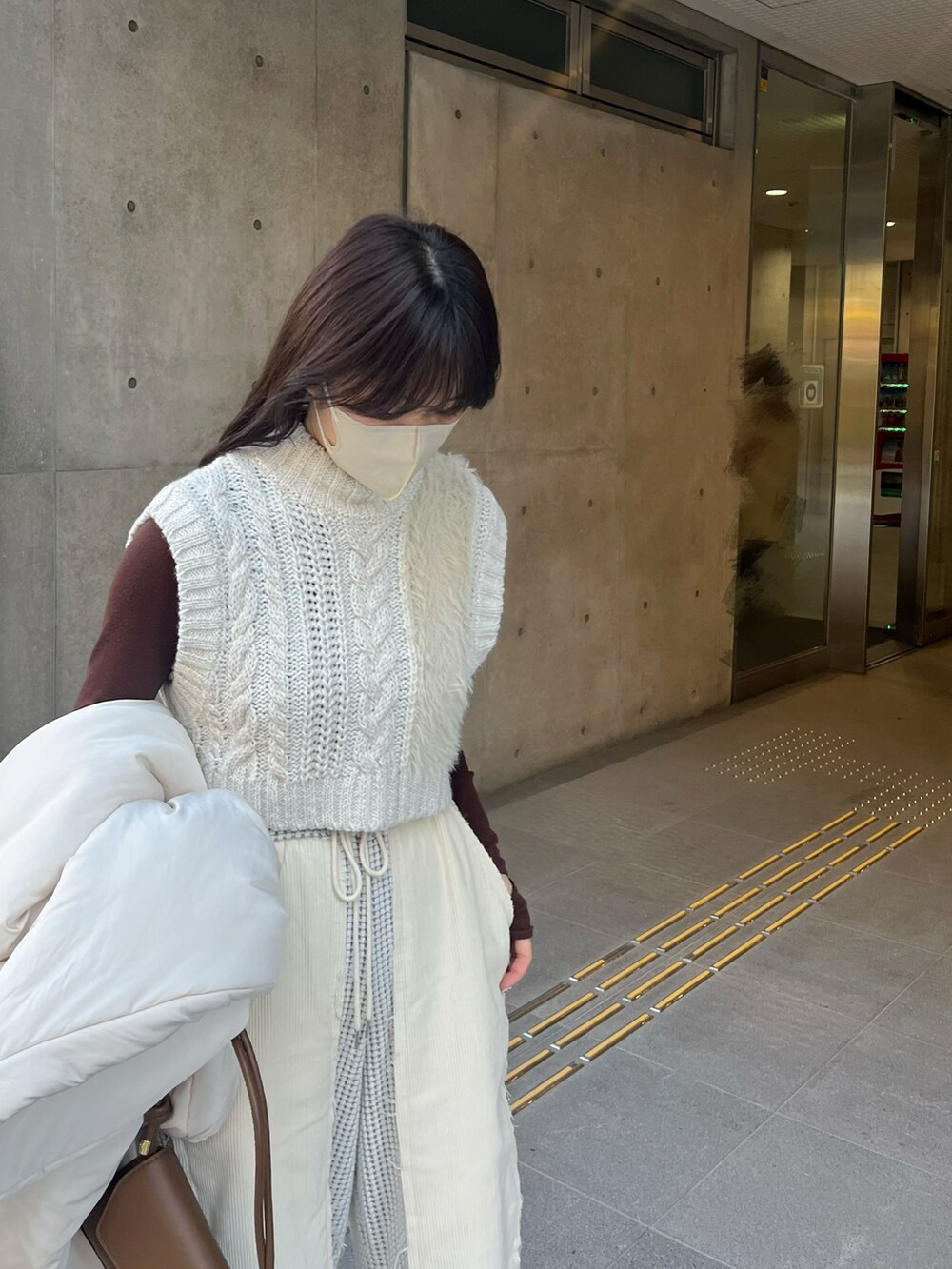 ホワイト系のダウンジャケット/コート、ホワイト系のニット/セーター、ブラウン系のニット/セーターを着用したレディースの冬コーディネートの3枚目の写真