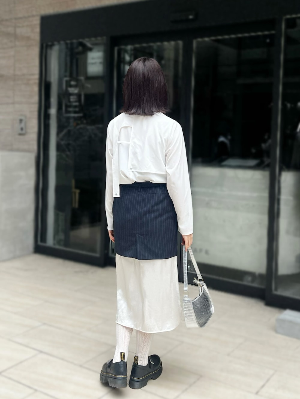 ブラック系のその他シューズ、ホワイト系のシャツ/ブラウス、ブルー系のスカートを着用したレディースの春コーディネートの2枚目の写真