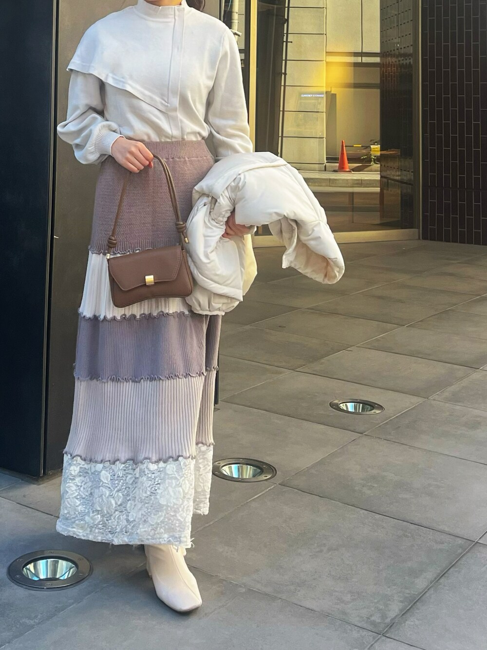 ベージュ系のニット/セーター、ホワイト系のダウンジャケット/コートを着用したレディースの冬コーディネートの2枚目の写真