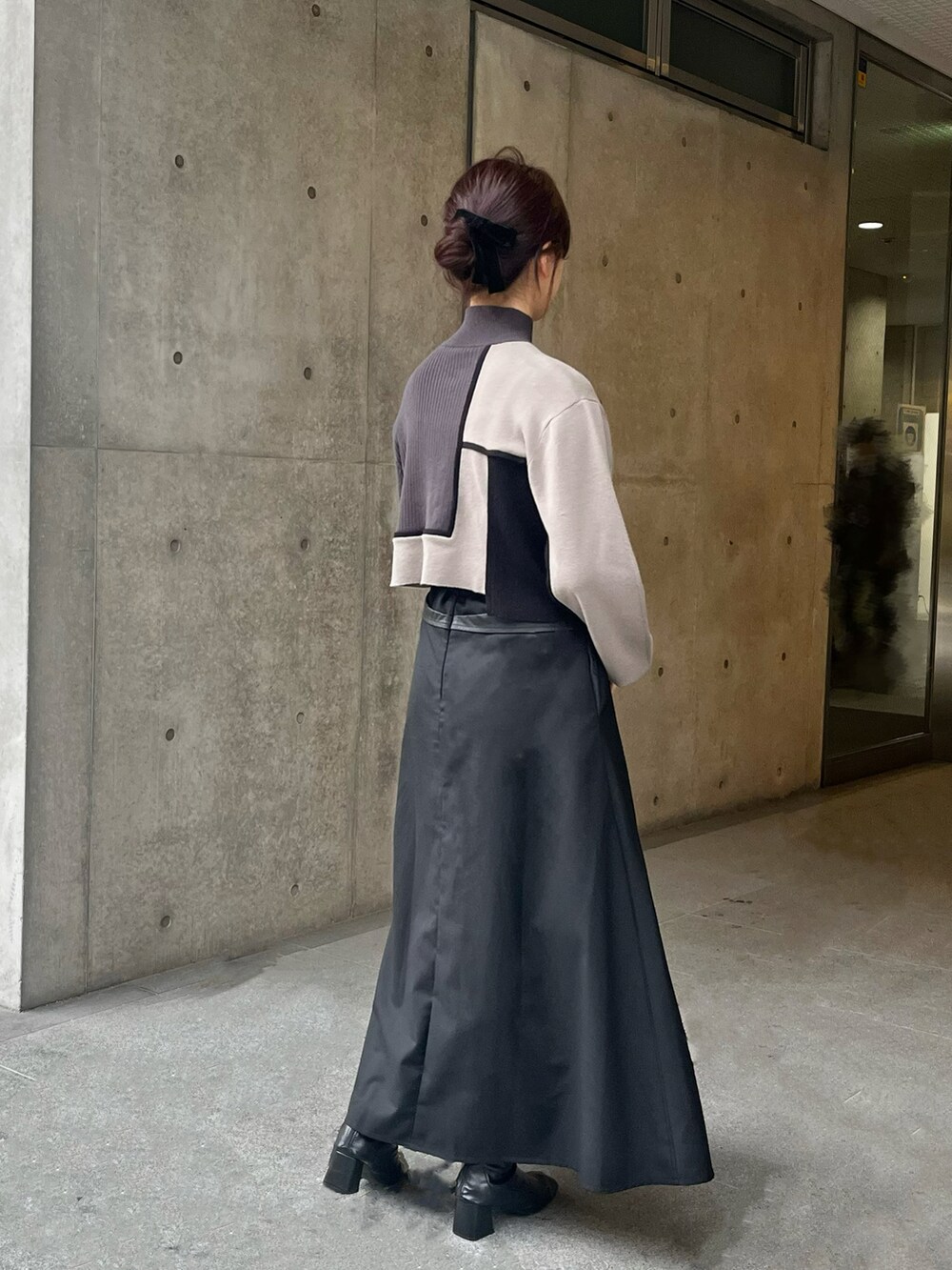 グレー系のニット/セーター、ブラック系のスカートを着用したレディースの春コーディネートの2枚目の写真