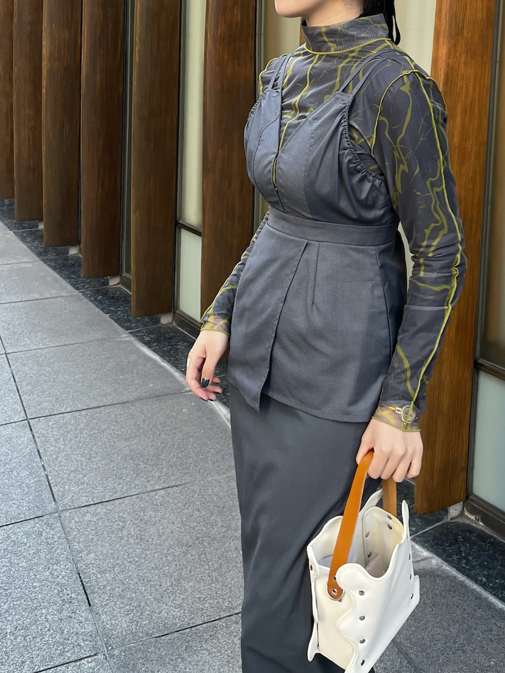 グレー系のワンピース、グレー系のTシャツ/カットソー、ブラック系のニット/セーターを着用したレディースの冬コーディネートの2枚目の写真