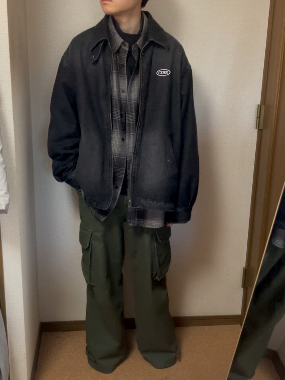 グリーン系のカーゴパンツ、ブラック系のデニムジャケット、グレー系のシャツ/ブラウスを着用したメンズの春コーディネートの2枚目の写真