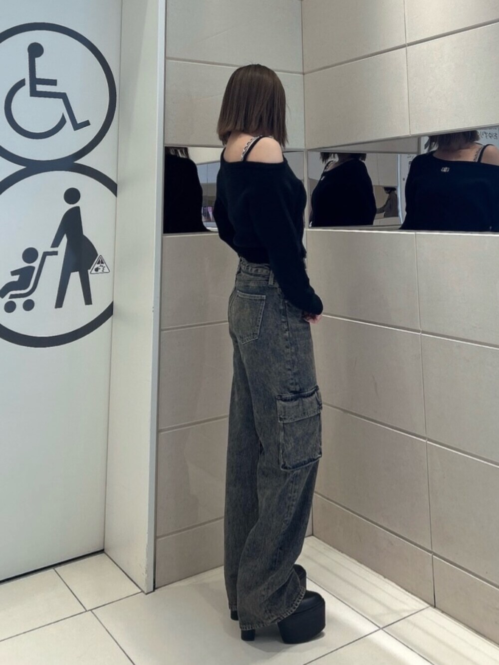 ブルー系のデニムパンツ、ブラック系のブーツ、ブラック系のニット/セーターを着用したレディースの秋コーディネートの2枚目の写真