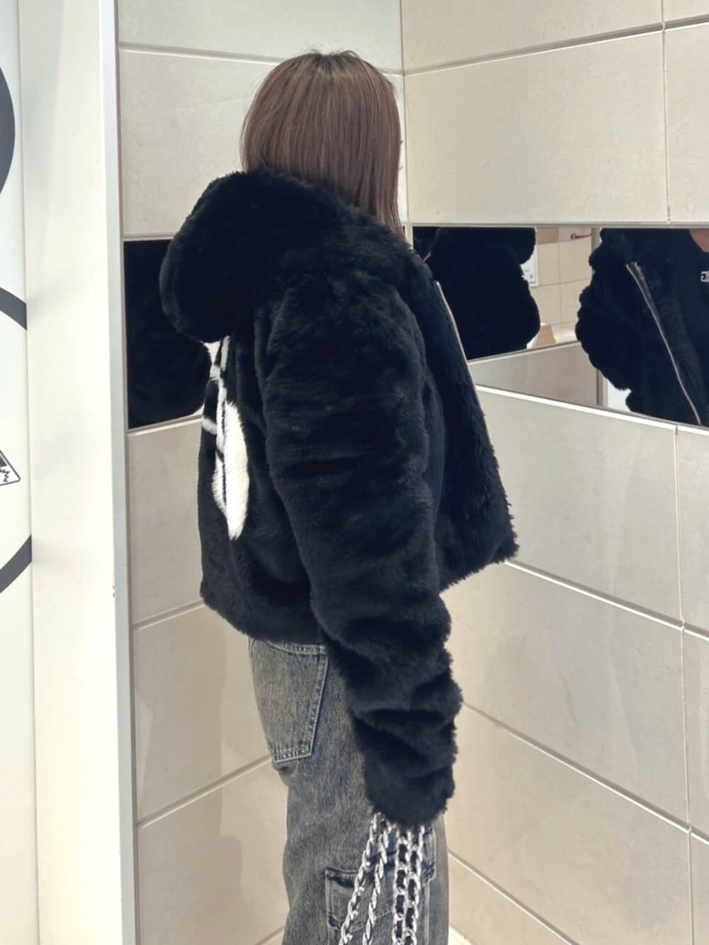 ブラック系のブルゾン、ブルー系のデニムパンツ、ブラック系のブーツを着用したレディースの秋コーディネートの5枚目の写真