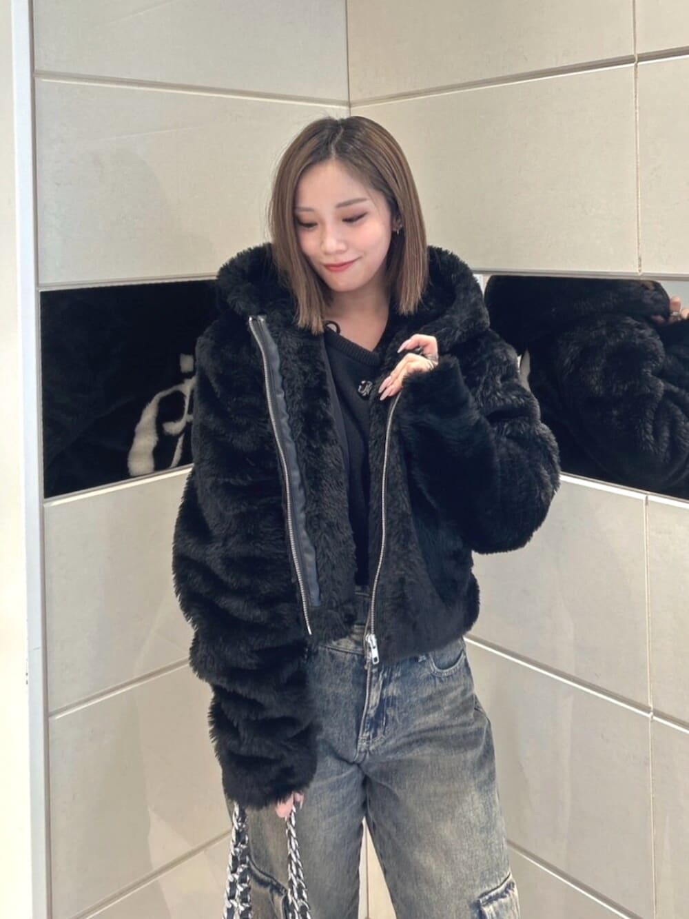 ブラック系のブルゾン、ブルー系のデニムパンツ、ブラック系のブーツを着用したレディースの秋コーディネートの4枚目の写真