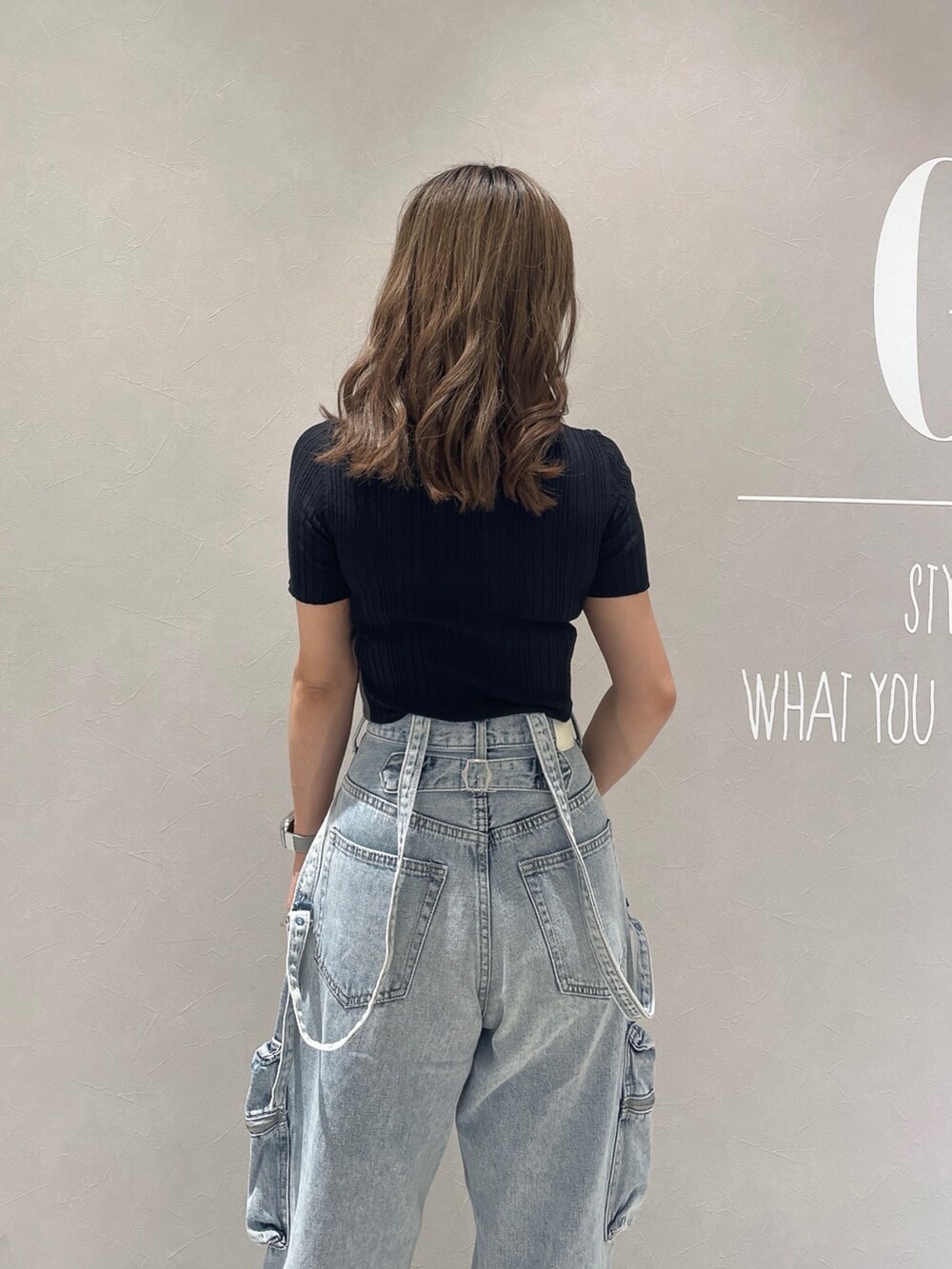 ブラック系のニット/セーター、ブルー系のデニムパンツ、ホワイト系のサンダルを着用したレディースの夏コーディネートの6枚目の写真