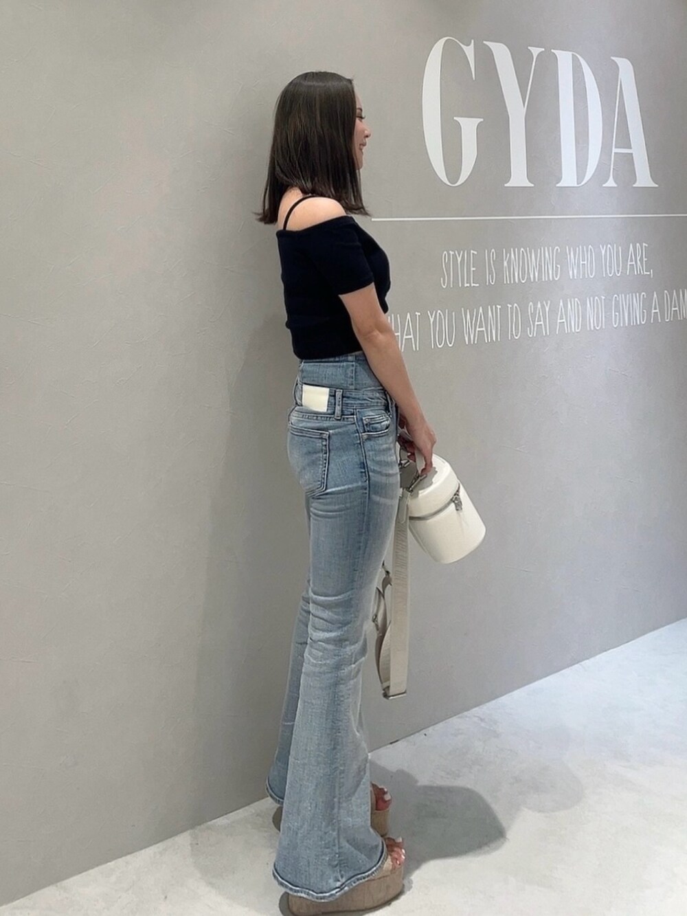 ブラック系のTシャツ/カットソー、ブルー系のデニムパンツ、ホワイト系のハンドバッグを着用したレディースの春コーディネートの2枚目の写真