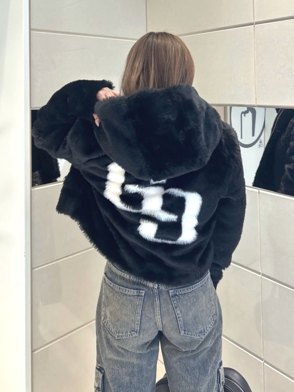 ブラック系のブルゾン、ブルー系のデニムパンツ、ブラック系のブーツを着用したレディースの秋コーディネートの6枚目の写真