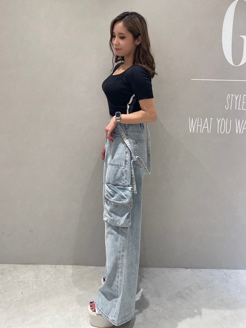 ブラック系のニット/セーター、ブルー系のデニムパンツ、ホワイト系のサンダルを着用したレディースの夏コーディネートの2枚目の写真