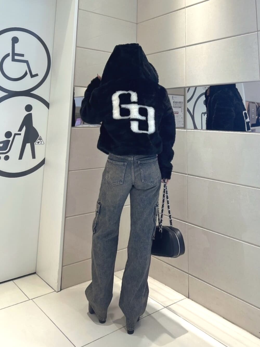 ブラック系のブルゾン、ブルー系のデニムパンツ、ブラック系のブーツを着用したレディースの秋コーディネートの3枚目の写真