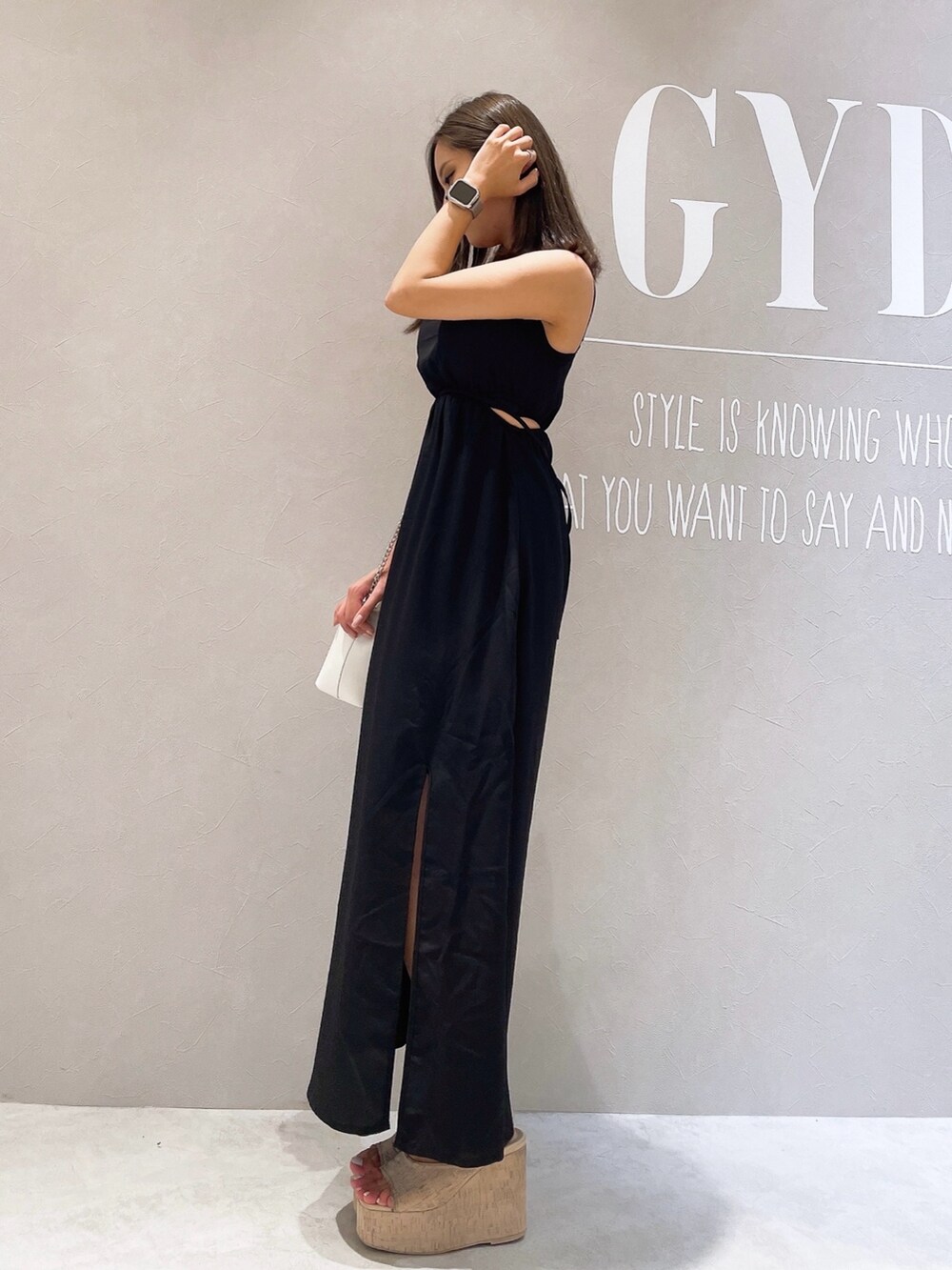 ブラック系のワンピース、ホワイト系のサンダル、ホワイト系のショルダーバッグを着用したレディースの夏コーディネートの2枚目の写真