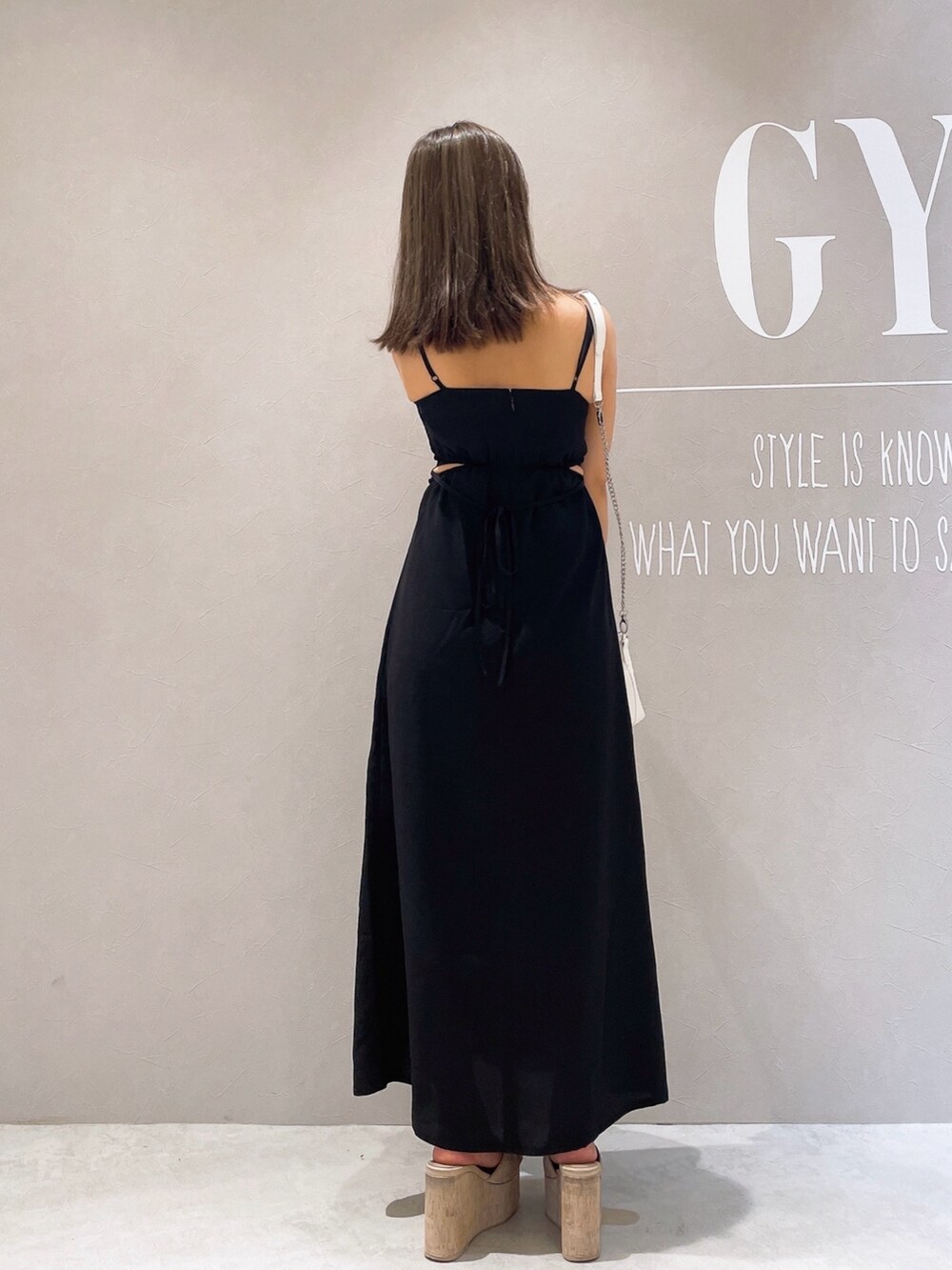 ブラック系のワンピース、ホワイト系のサンダル、ホワイト系のショルダーバッグを着用したレディースの夏コーディネートの3枚目の写真