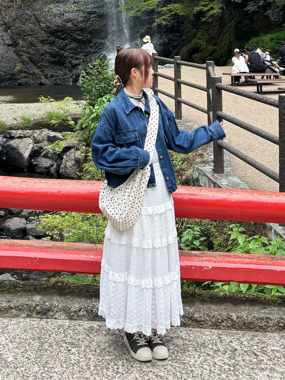 ホワイト系のスカート、ホワイト系のショルダーバッグ、ブルー系のデニムジャケットを着用したレディースの春コーディネートの2枚目の写真