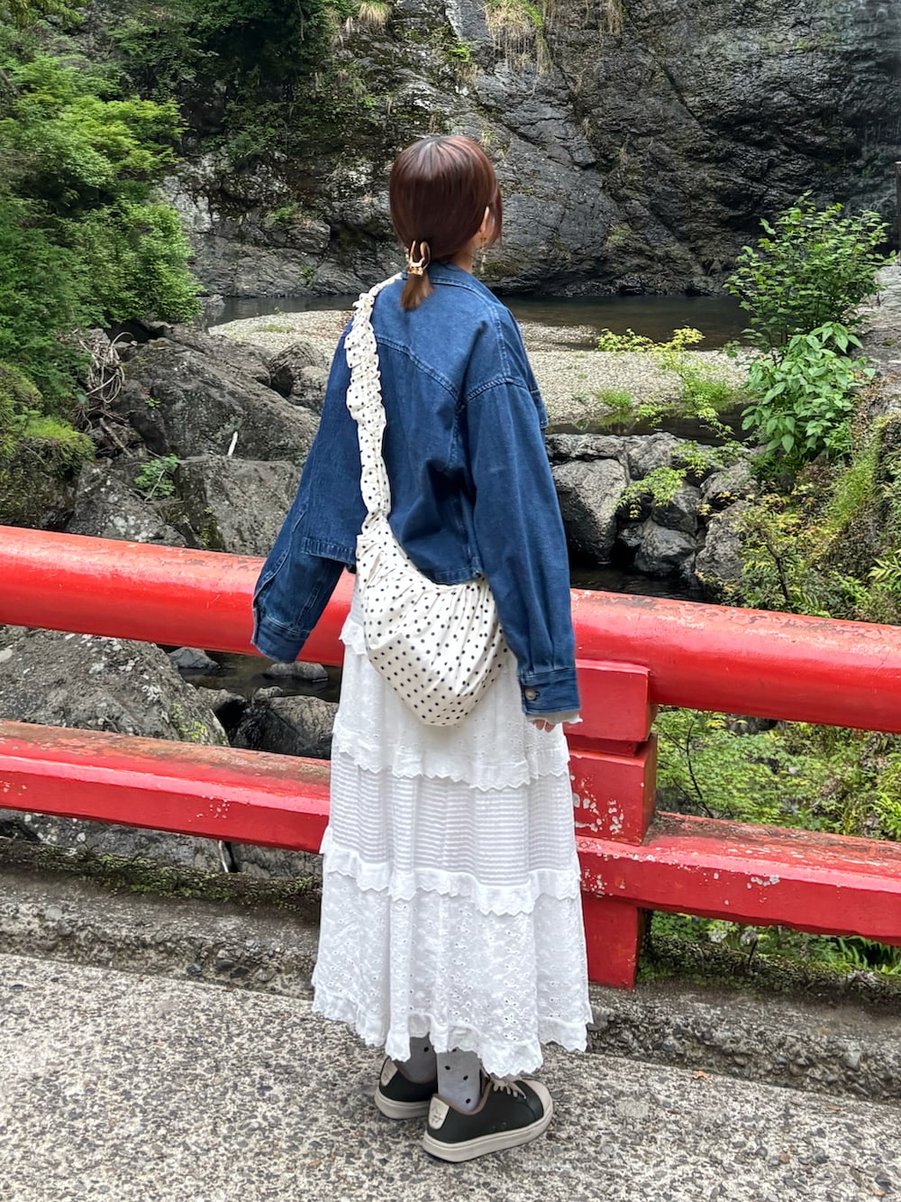 ホワイト系のスカート、ホワイト系のショルダーバッグ、ブルー系のデニムジャケットを着用したレディースの春コーディネートの3枚目の写真