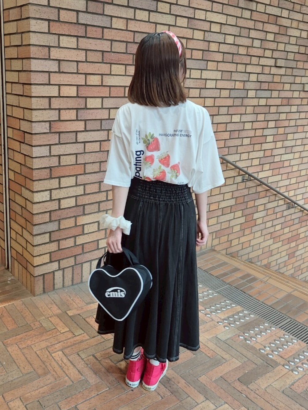 ホワイト系のTシャツ/カットソー、ブラック系のデニムスカート、レッド系のスニーカーを着用したレディースの夏コーディネートの2枚目の写真