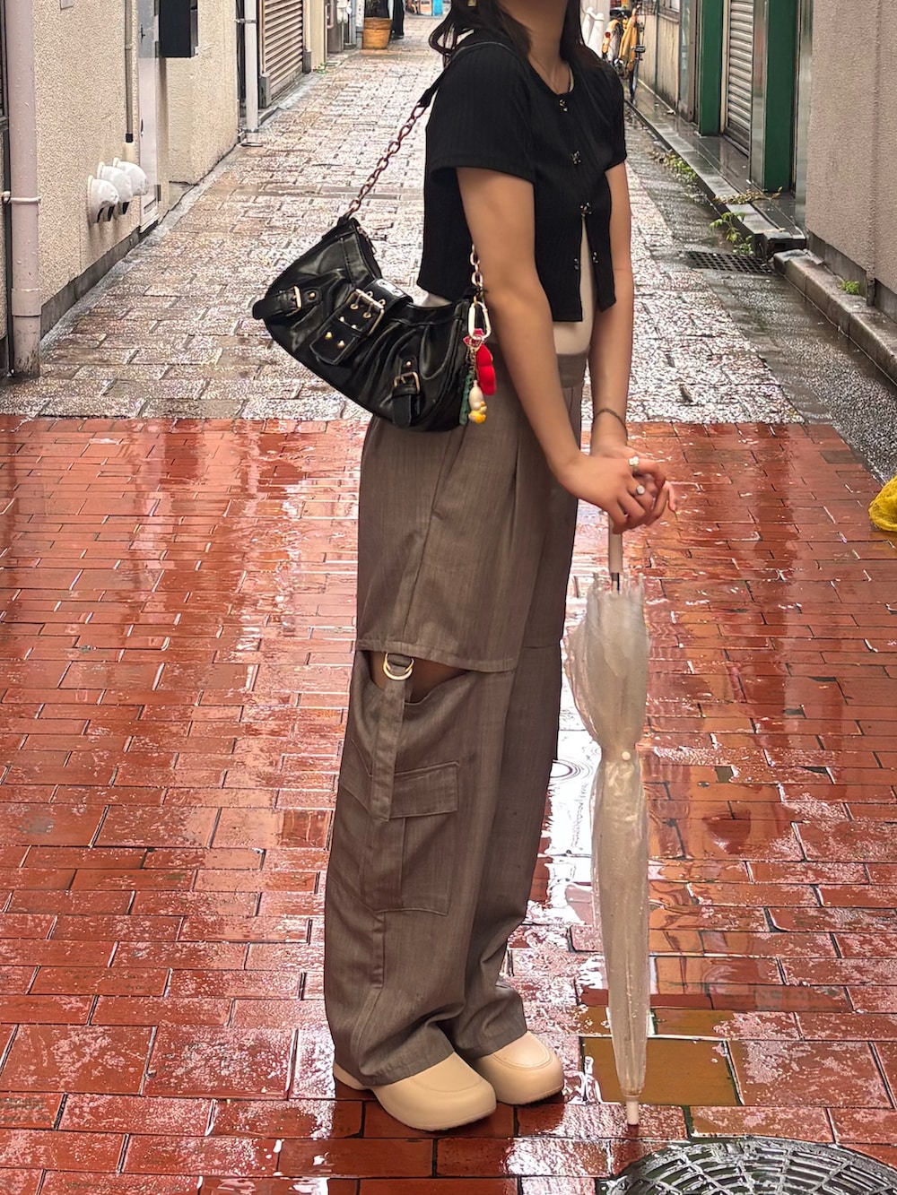 グレー系のパンツ、ホワイト系のシューズ、ブラック系のトップスを着用したレディースの夏コーディネートの2枚目の写真