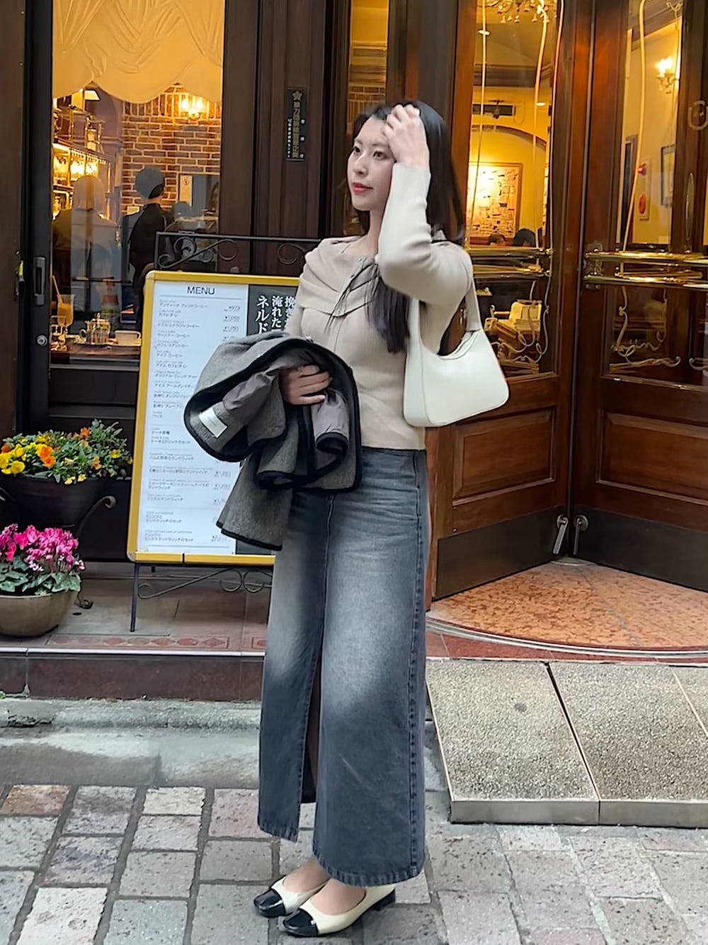 ベージュ系のニット/セーター、ブラック系のデニムスカート、その他のシューズを着用したレディースの春コーディネートの2枚目の写真