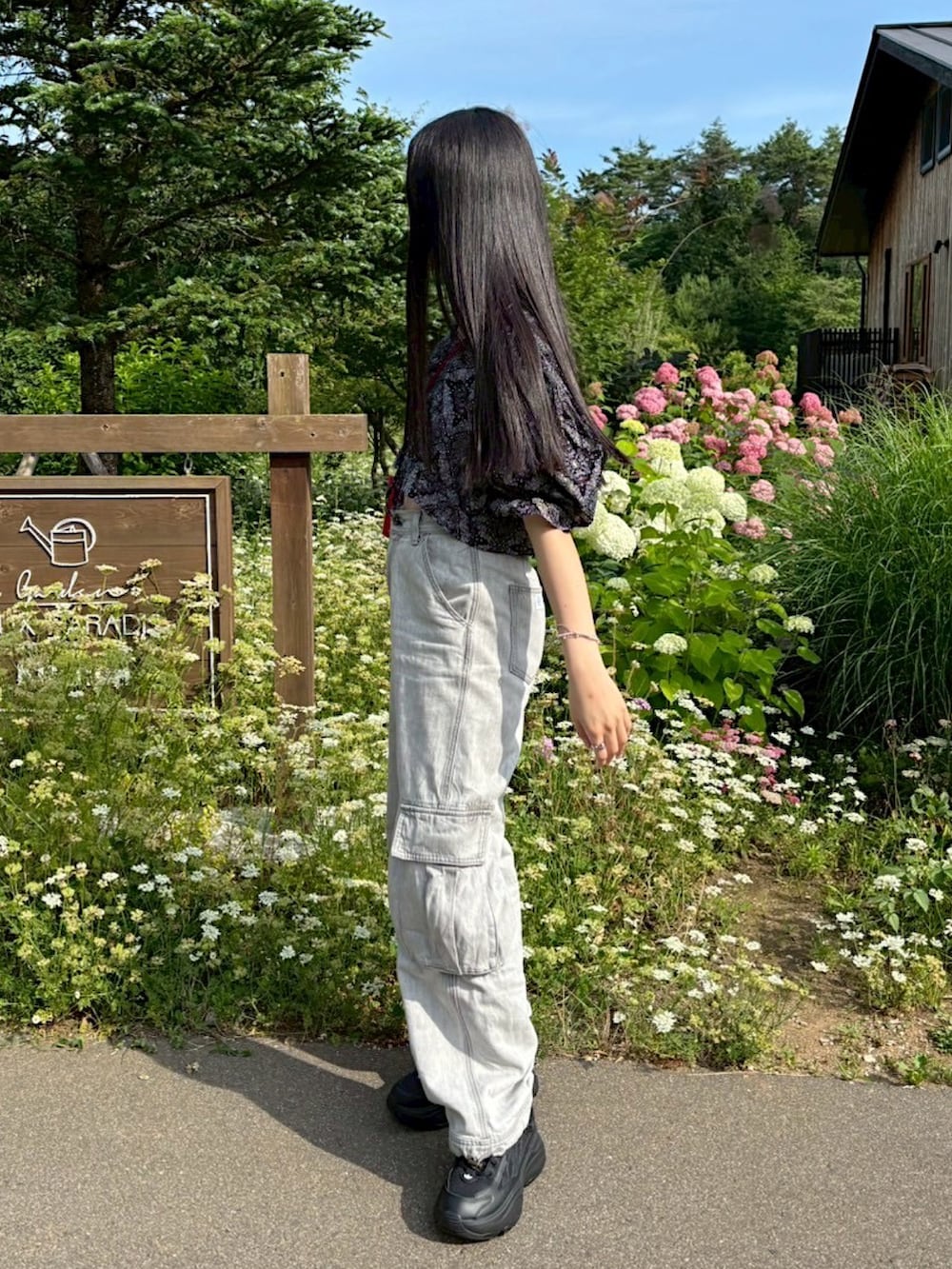 ブラック系のスニーカー、グレー系のカーゴパンツ、レッド系のショルダーバッグを着用したレディースの夏コーディネートの2枚目の写真