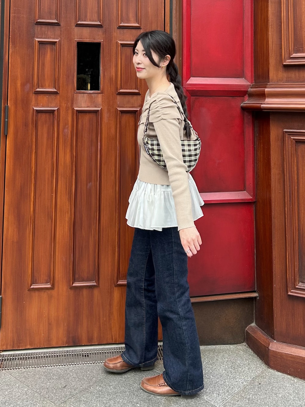 ブルー系のデニムパンツ、ホワイト系のスカート、ベージュ系のニット/セーターを着用したレディースの春コーディネートの2枚目の写真