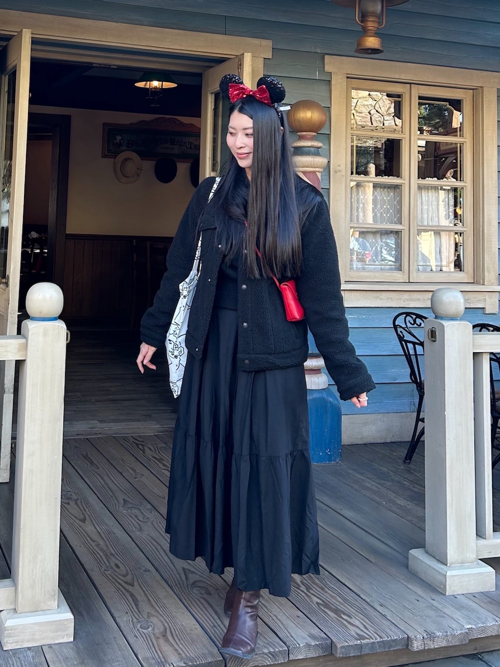 レッド系のショルダーバッグ、ブラック系のスカート、ブラック系のジャケット/アウターを着用したレディースの冬コーディネートの2枚目の写真