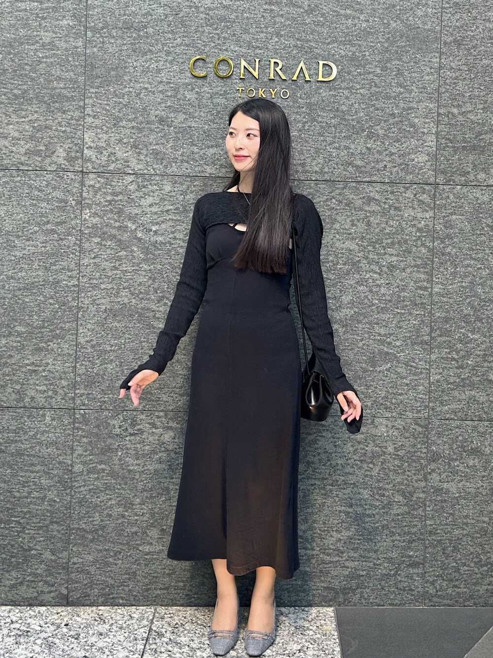 ブラック系のワンピース、ブラック系のパンプス、ブラック系のショルダーバッグを着用したレディースの秋コーディネートの3枚目の写真