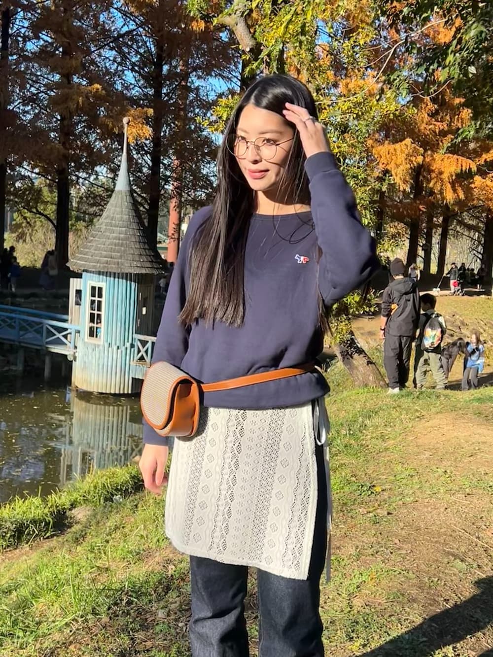 ブルー系のスウェット、ブラウン系のボディバッグ/ウエストポーチ、ホワイト系のスカートを着用したレディースの秋コーディネートの3枚目の写真