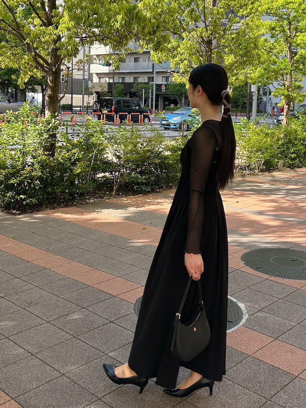 ブラック系のハンドバッグ、ブラック系のパンプス、ブラック系のトップスを着用したレディースの春コーディネートの3枚目の写真