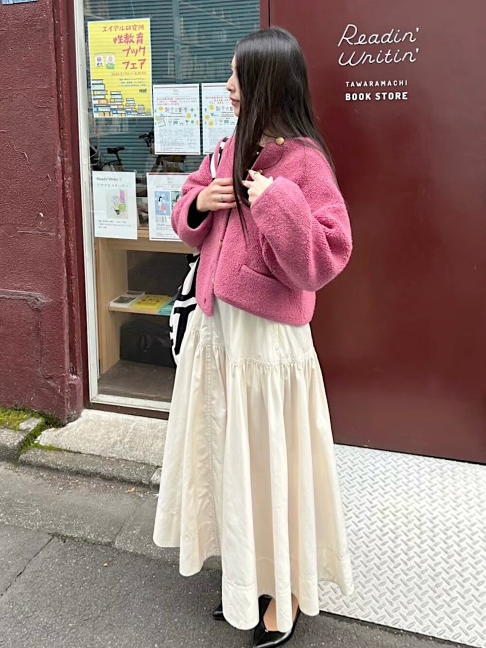 ピンク系のカーディガン/ボレロ、ホワイト系のスカート、ブラック系のパンプスを着用したレディースの秋コーディネートの2枚目の写真