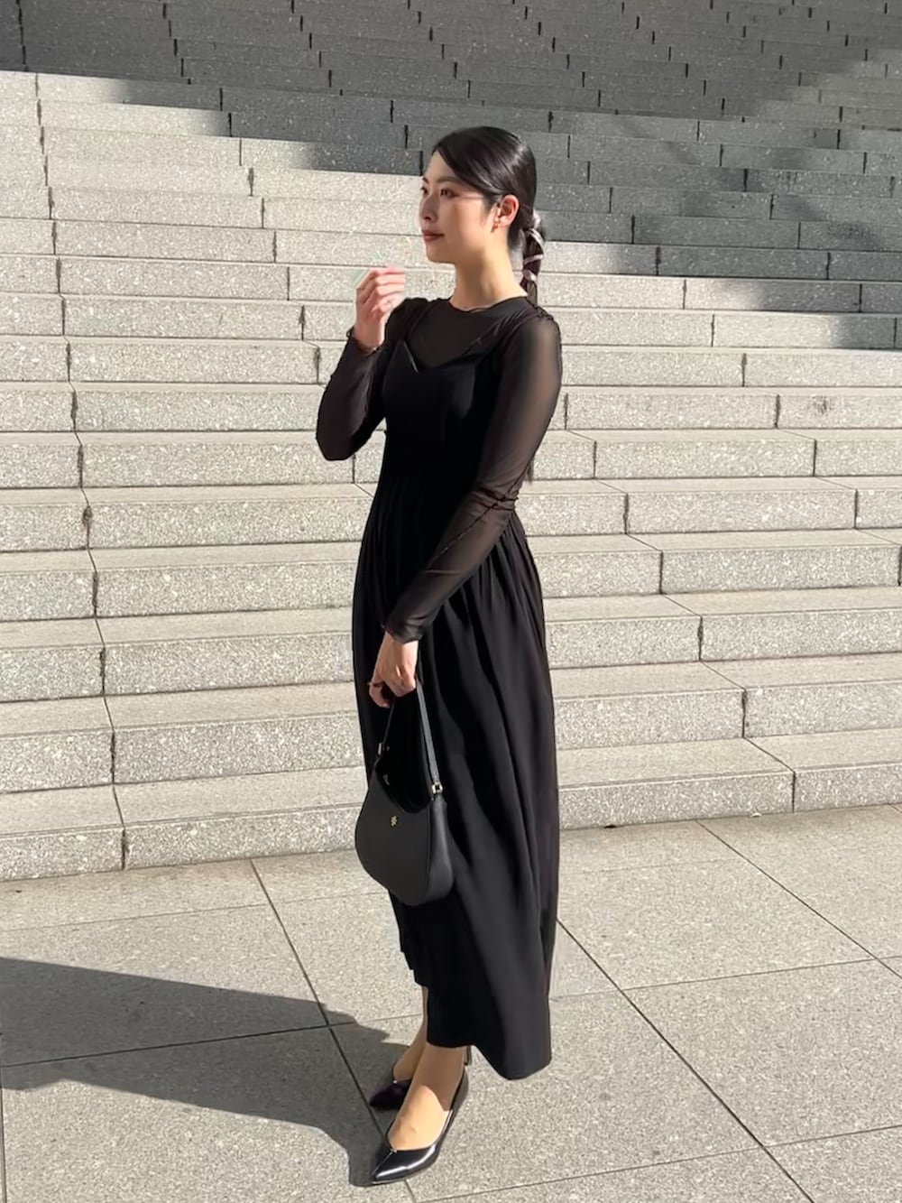 ブラック系のハンドバッグ、ブラック系のパンプス、ブラック系のトップスを着用したレディースの春コーディネートの2枚目の写真